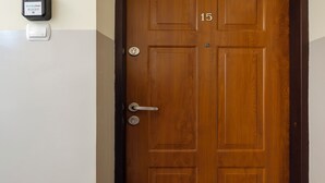A wooden door with a numeric keypad lock, a doorbell, and a wall-mounted device. - Uniwersytecka Standard Studio (Lódz)