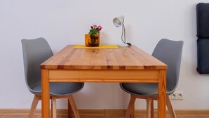 A wooden dining table with two grey chairs, a small vase with flowers, and a desk lamp. - Uniwersytecka Standard Studio (Lódz)