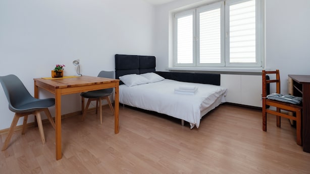 A small, well-lit room with a bed, a desk, and a chair. - Uniwersytecka Standard Studio (Lódz)