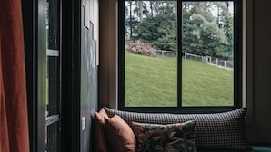 Une pièce dotée d’une grande fenêtre, d’un banc en bois agrémenté de coussins et d’un luminaire suspendu.
