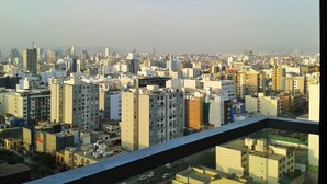 Un paisaje urbano con numerosos rascacielos, cielo despejado y una cadena montañosa distante.