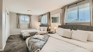 Habitación de hotel con dos camas, un ventanal con persianas, una lámpara de techo y una mesita de noche con lámpara.