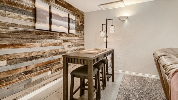 Un comedor con pared de madera rústica, una mesa con sillas e iluminación colgante.