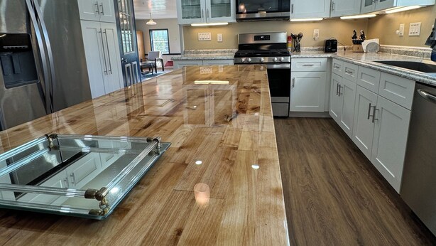 Una cocina moderna con una isla de madera, electrodomésticos de acero inoxidable y armarios blancos.