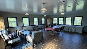 Un salón amplio con suelo de madera, zona de comedor y ventanas grandes.