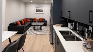 Una cocina moderna con armarios oscuros, un refrigerador de acero inoxidable y una encimera blanca.