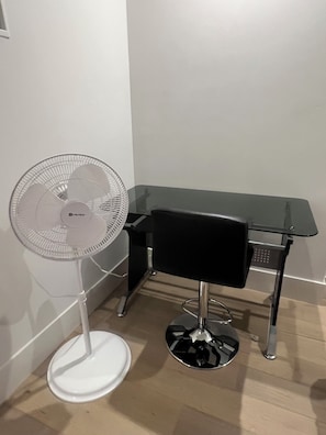 Work in comfort with a high-back office chair and a spacious desk against a clean white wall.