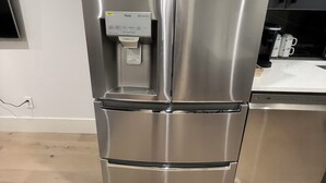 Un refrigerador de acero inoxidable con dispensador de agua y compartimento congelador.