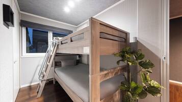 A bunk bed room with a wooden ladder, a window with a view, and a plant.