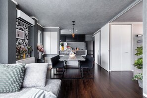 A modern kitchen with dark cabinets, a dining table, and a sofa in the foreground. - THE EXEPAREL (Kushiro)