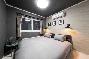A modern bedroom with a large bed, a window with curtains, an air conditioner, and framed pictures on the wall. - THE EXEPAREL (Kushiro)