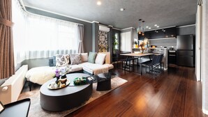 Un salon moderne avec un canapé, une table basse et un coin repas, la cuisine étant visible au fond.