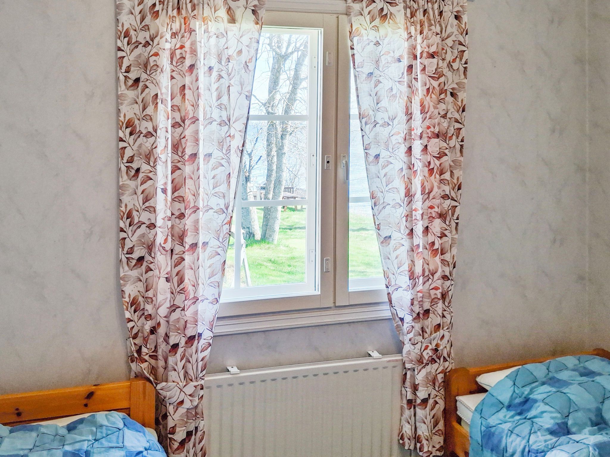 Une chambre avec une fenêtre, deux lits et un radiateur.