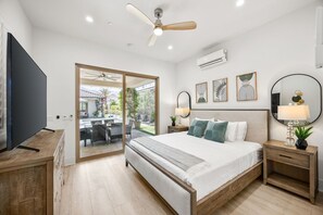 A modern bedroom with a large bed, bedside tables, a ceiling fan, and a TV. - Desert Jade: Pool, Spa, EV Charger, BBQ, and more! (La Quinta)
