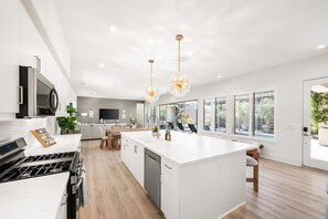 A modern kitchen with a central island, built-in appliances, and pendant lighting. - Desert Jade: Pool, Spa, EV Charger, BBQ, and more! (La Quinta)