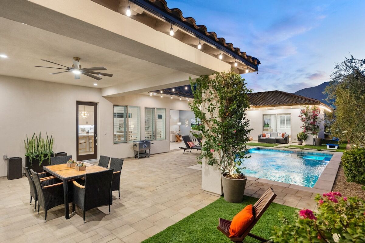 An outdoor patio with a pool, seating area, and a ceiling fan.