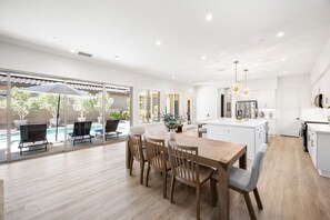 A modern kitchen with white cabinetry, a central island, and a dining area with a wooden table and chairs.