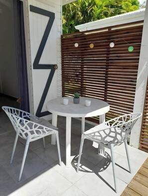 Un patio con una mesa blanca y dos sillas blancas, una valla de madera y un letrero grande con la letra 'Z' en la pared.