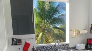 Eine moderne Küche mit großem Fenster, einer Spüle und einem Mülleimer.