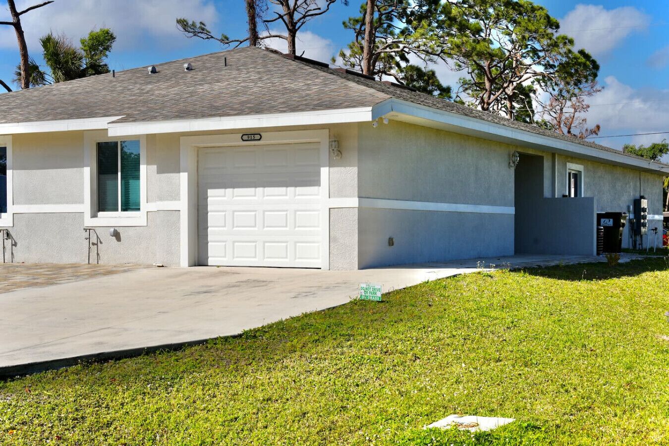 A single-story house with a garage, a driveway, and a grassy lawn.