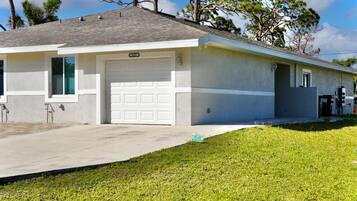 A single-story house with a garage, a driveway, and a grassy lawn.