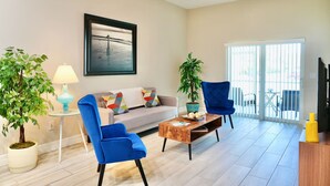 A living room with a sofa, two blue chairs, a coffee table, a lamp, and two potted plants. - SWFL: Lake McGregor 3 bedroom Home - Entire Home! (Fort Myers)