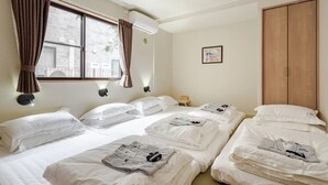 Une chambre d’hôtel avec deux lits, une armoire en bois, une fenêtre avec des rideaux et un climatiseur fixé au mur.