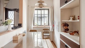 Une cuisine moderne avec une table en bois, un luminaire suspendu et une fenêtre avec des rideaux.