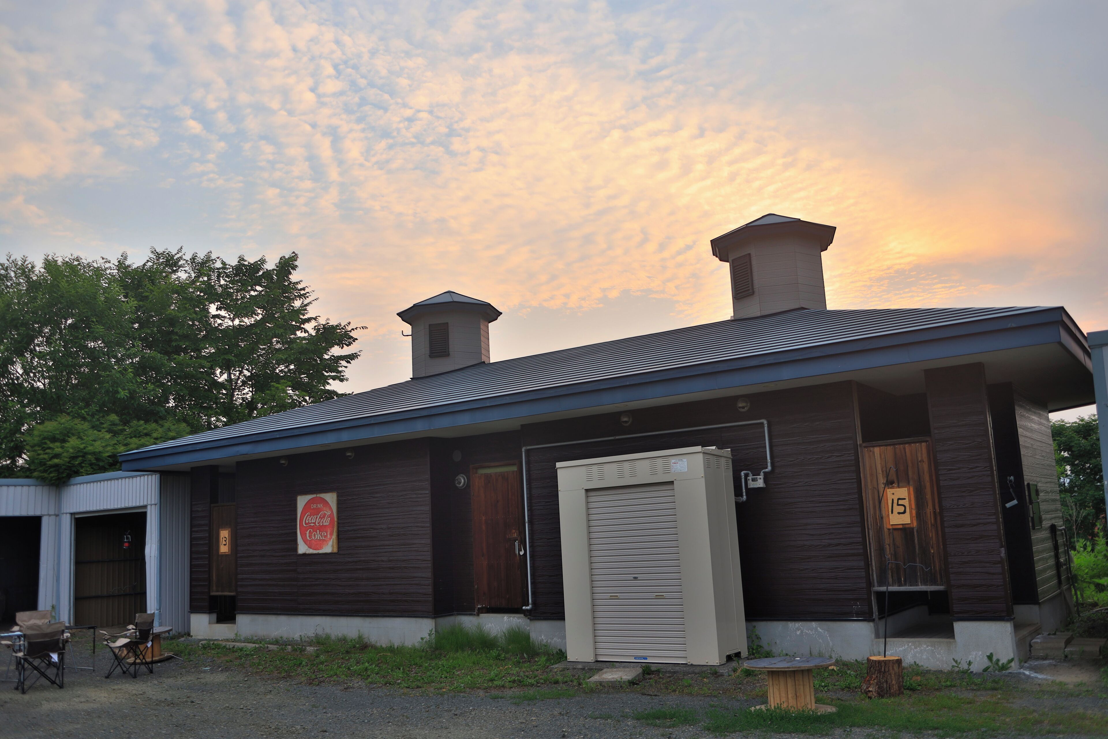 A building with a dark exterior, a wooden door, and a sign that reads "Coca-Cola".