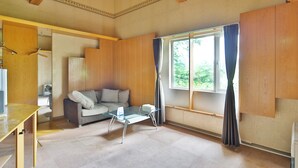 A spacious living room with a glass coffee table, a sofa, and a large window with curtains. - STARRY SKY COTTAGE 12 (Kitami)