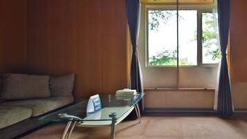 A room with a glass table, a sofa, and a window with curtains.