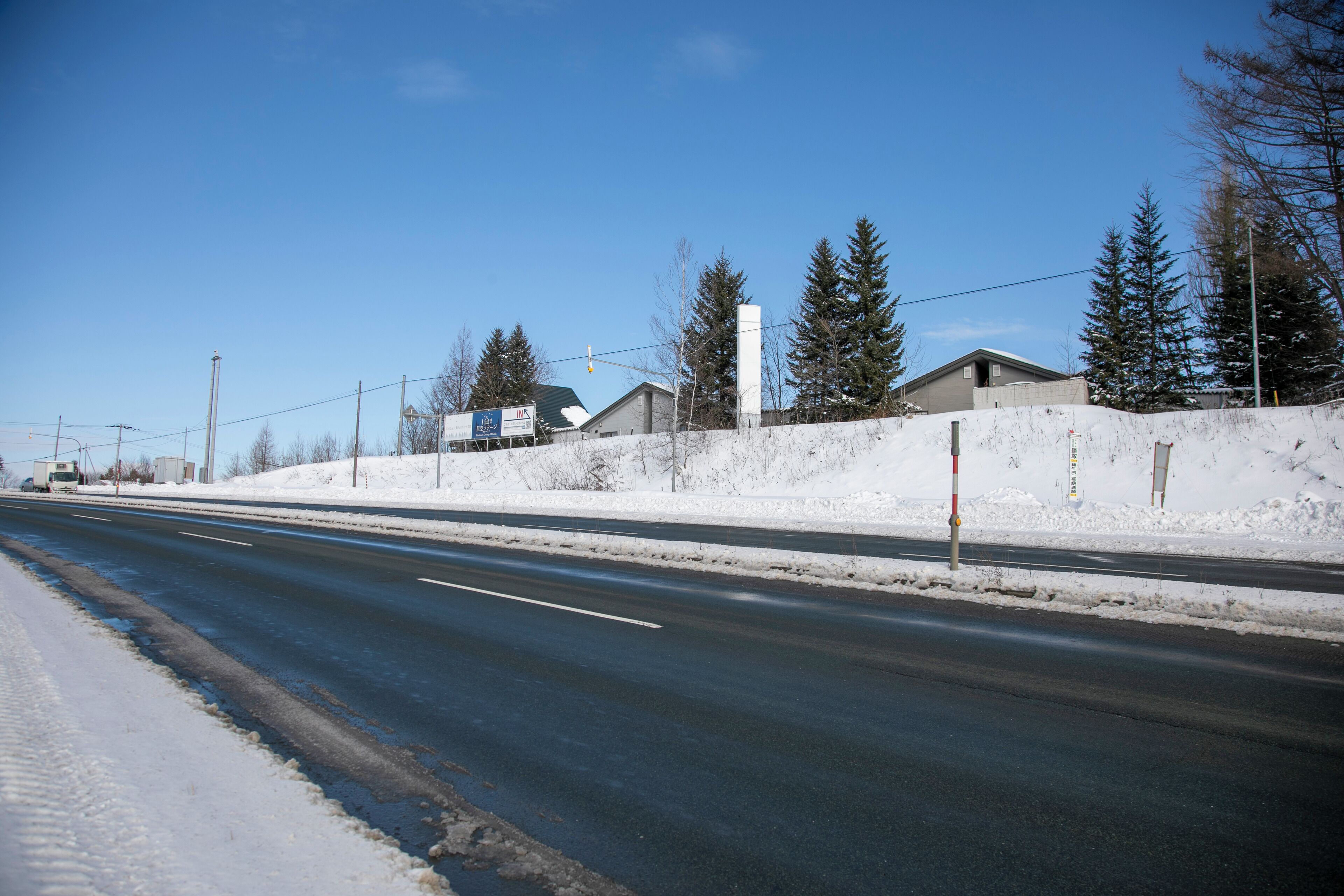 A road with snow on the sides and a clear blue sky.