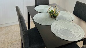 A dining table with placemats and a hexagonal planter with plants.