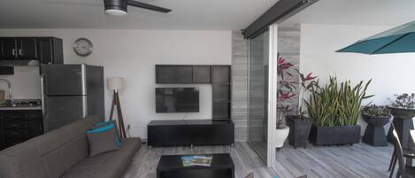 Una sala de estar moderna con sofá, mesa de centro, televisor y ventilador de techo.
