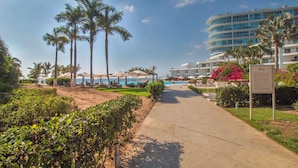 Un resort con piscina, palmeras y un camino que lleva a un edificio.