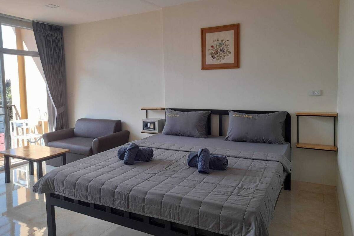 Una camera d'albergo con un letto, due sedie, un tavolino, un comodino e una finestra con tende.
