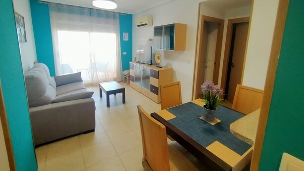 A living room with a sofa, a dining table, and a small kitchen area. - ACV - Torremar-2ª Linea Planta 3 Sur (OROPESA)