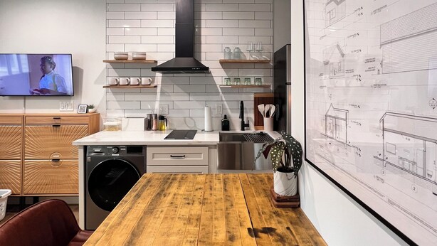 A modern kitchen with a wooden table, built-in appliances, and a large window. - Cozy Cottage in Sacramento with Fire Pit & Backyard Movie Nights (Sacramento)