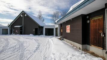 Un edificio cubierto de nieve con un cartel de Coca-Cola, una puerta de garaje y un ventanal grande.