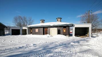Un bâtiment dont le toit est recouvert de neige et qui possède une porte de garage.