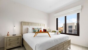 Ein Schlafzimmer mit Bett, Nachttisch und einem Fenster mit Blick auf Gebäude.