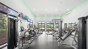 Ein modernes Fitnessstudio mit verschiedenen Trainingsgeräten, großen Fenstern und einem sauberen, gut beleuchteten Innenraum.