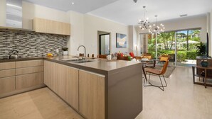 A modern kitchen with a large island, wooden cabinets, and a tiled backsplash. - Amazing 3BR Eagle Beach Condo @LeVent  Pool  GYM (Noord)