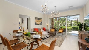 A modern dining area with a glass table, leather chairs, and a view of the outdoors through large windows. - Amazing 3BR Eagle Beach Condo @LeVent  Pool  GYM (Noord)