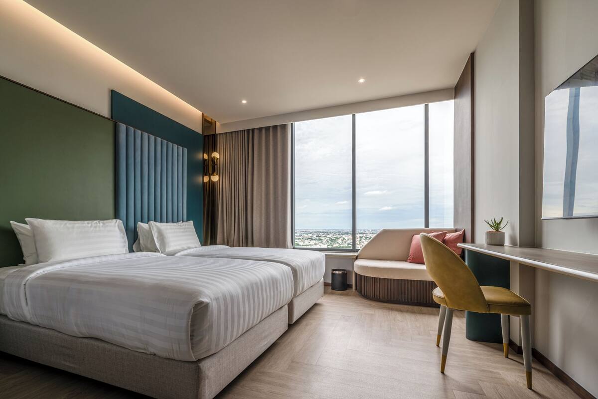 Una habitación de hotel moderna con una cama grande, un escritorio y vistas a la ciudad.