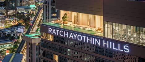 A high-rise building named Ratchayothin Hills with a rooftop pool and a view of the cityscape.