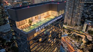 A high-rise hotel with a rooftop pool and a view of the cityscape. - The Quarter Ratchayothin by UHG (Bangkok)