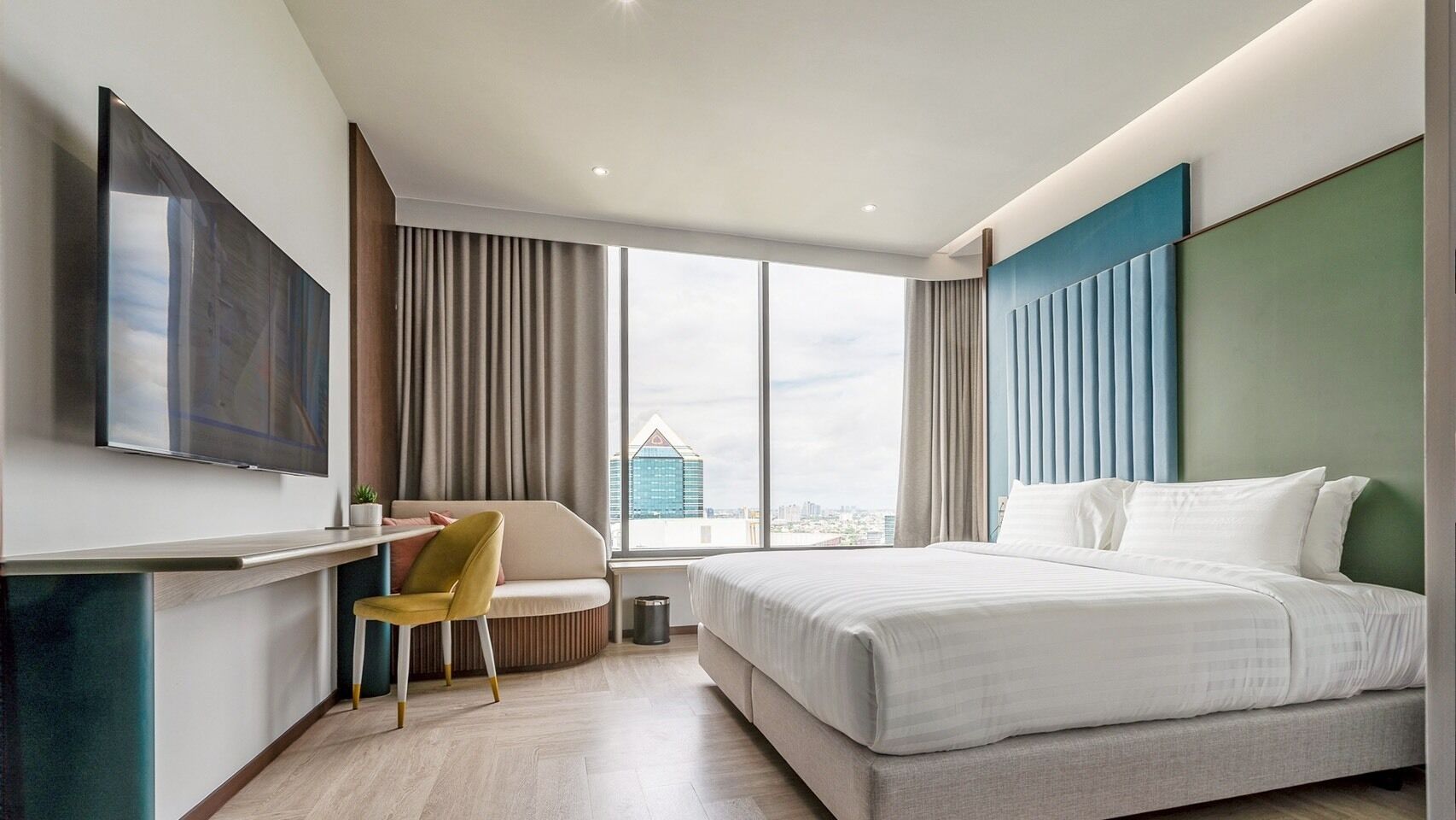 A modern hotel room with a large bed, a desk, and a television.
