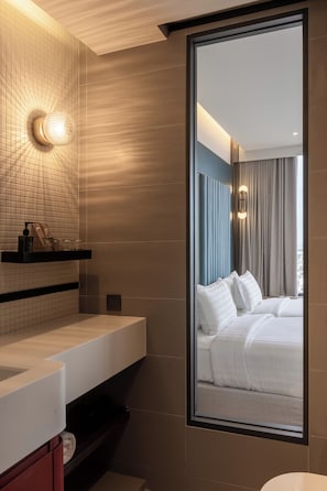Un baño moderno con un espejo grande, un lavabo blanco y un perchero para toallas.