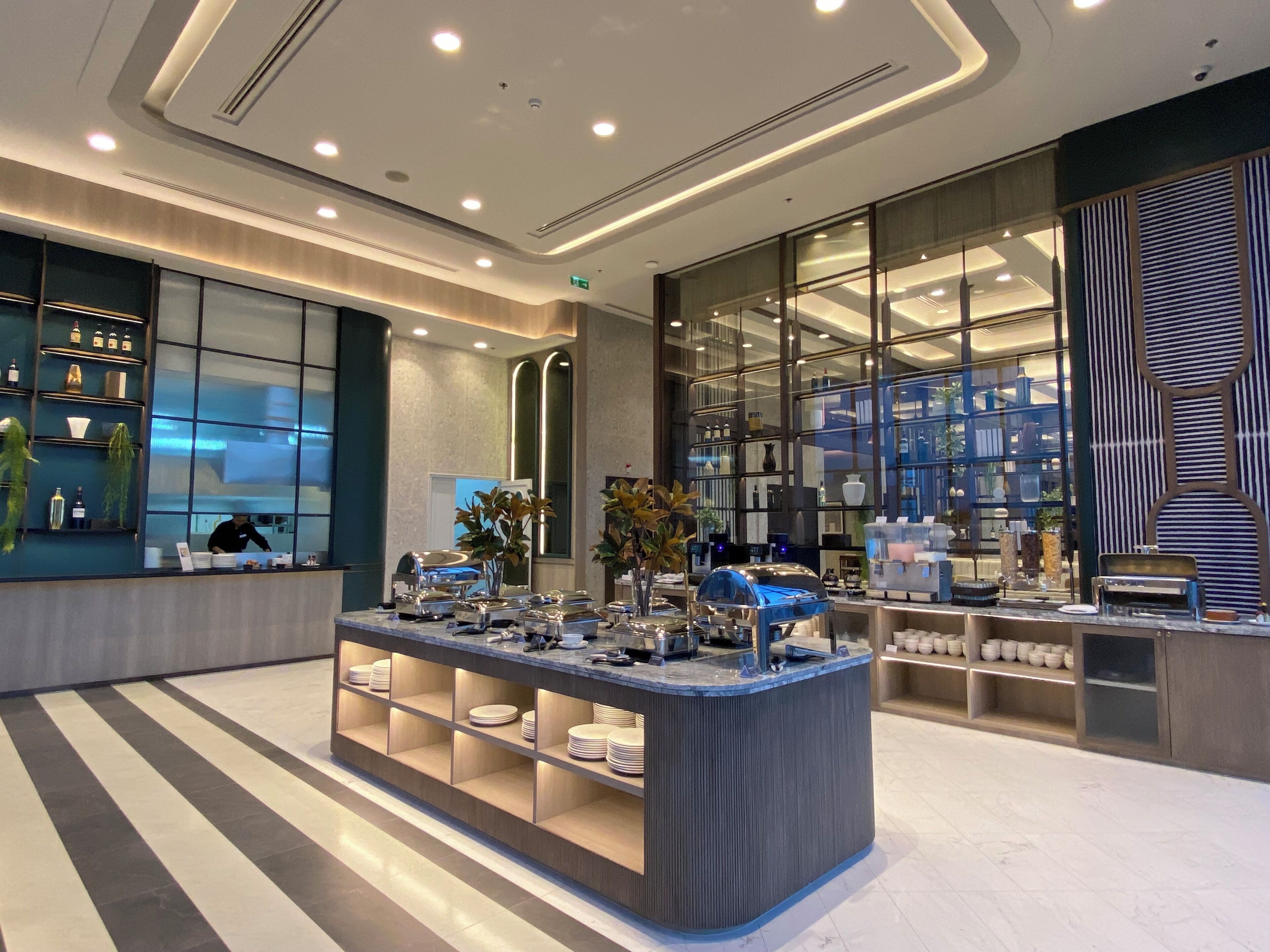 A modern hotel lobby with a central reception desk, glass display cases, and a clean, contemporary design.